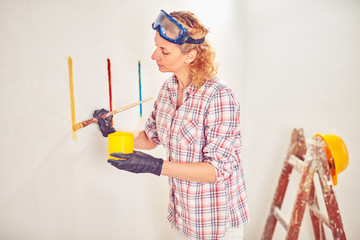 Working woman plastering / painting walls inside the house.
