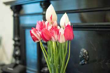 pink and white tulips in a vase on the piano background