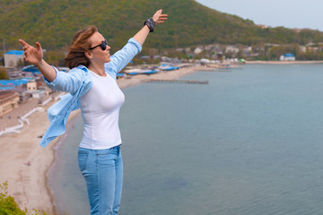 Happy tourist woman climbed to the top of the mountain. Emotions of joy and happiness. Mountain and sea in the background. Close up