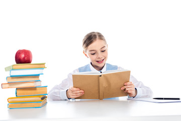 cute schoolgirl sitting at desk and reading book Isolated On White