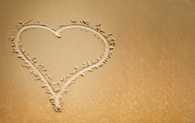 Finger drawn heart on the sand, symbol of love with copy space