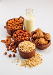 Different types of vegan milk, almond milk, oat milk, hazelnut milk and walnut milk on a white background