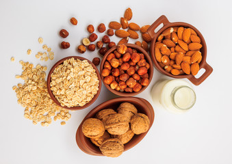 Different types of vegan milk, almond milk, oat milk, hazelnut milk and walnut milk on a white background