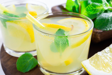 Summer drink of lemon and mint, or lemonade, on dark wooden table.
