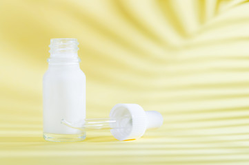 Natural cosmetics: serum with dropper on yellow background with shadow.