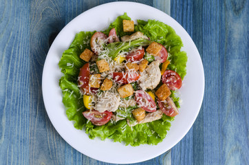 salad with poultry, vegetables and grated cheese on a white plate top view