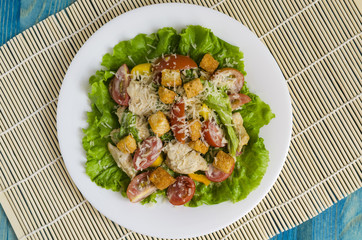 salad with poultry, vegetables and grated cheese on a white plate top view