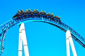 Blue spooky scary roller coaster fast riding with loop and yellow seats in the amusement park in...