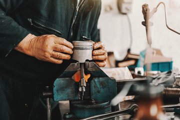 Auto mechanic putting cylinder on clamp while standing in workshop.
