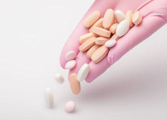 tablets lie on the palm. Hand in pink glove holds pills