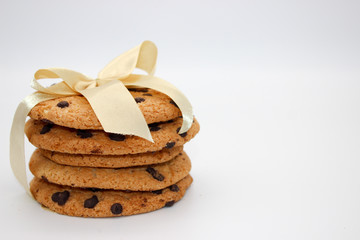 Oatmeal cookies with chocolate drops, tied with a golden ribbon, isolated on white background