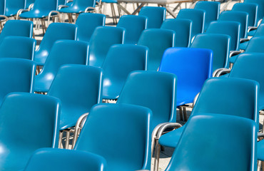 Obraz premium Trying to fit in - In a sea of plastic blue chairs, one of them is not quite the same hue of the other, but it's trying to fit in