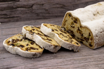 The three slices and the main part of Stollen on a wooden background. Traditional German Christmas...