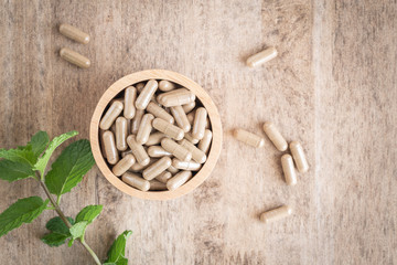 Herbal capsules  in cup on wooden table background . Top view of medicine for healthy.