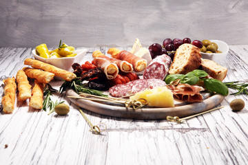 antipasto various appetizer. Cutting board with prosciutto, salami, cheese, bread and olives on white wooden background