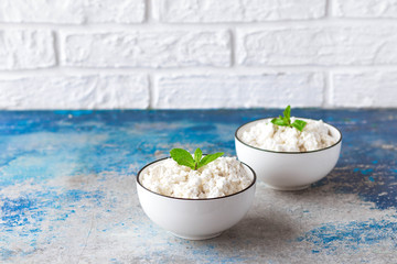 Cottage cheese with mint leaves on a light background in white bowl
