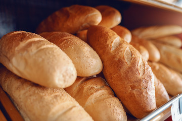 Close up of fresh delicious loafs of bread in row on shelves ready for sale. Bakery interior.