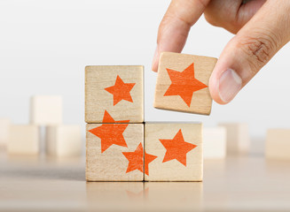 Hand putting the last piece of wooden blocks with the five star symbol. The best rating, the best...