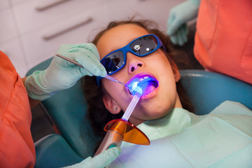 Girl at the dentist getting treatment with dental blue light