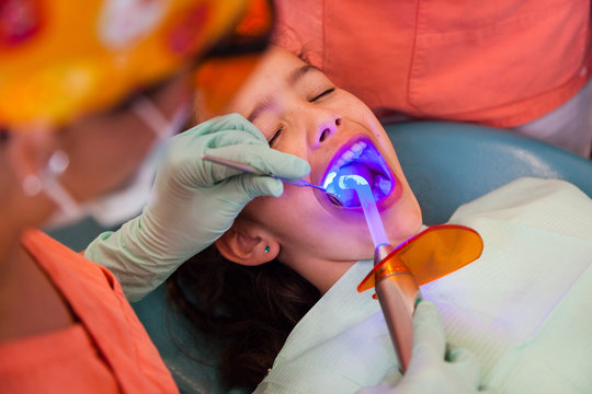Girl at the dentist getting treatment with dental blue light