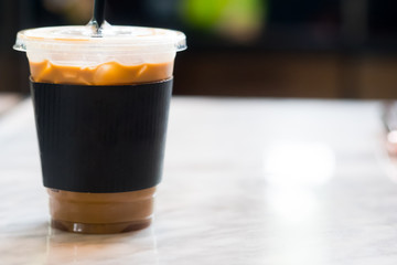 Iced coffee with black paper sleeve on table