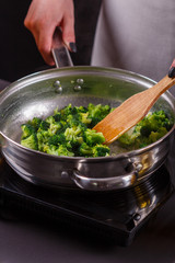 young woman in a gray apron roasts cauliflower broccoli