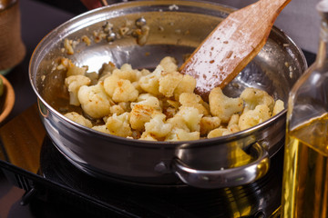 young woman in a gray apron roasts cauliflower broccoli