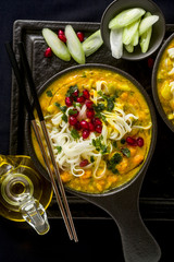 laks with pumpkin and coconut milk, rice noodles, broccoli and pomegranate seeds in portioned black plates onlaksa with pumpkin and coconut milk, rice noodles, broccoli and pomegranate seeds 