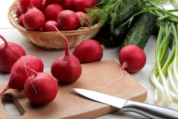 fresh radish. Spring fresh vegetables radishes, cucumber, green onions and greens on a white wooden table. ingredients for cooking.