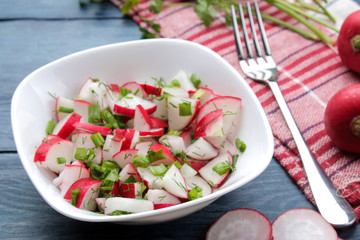 Salad of fresh radishes and fresh herbs on a blue wooden table. Spring vegetable salad. ingredients for cooking salad.