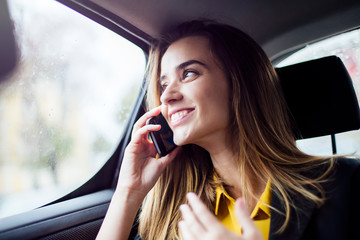 Fototapeta na wymiar Young businesswoman talking on mobile phone in car