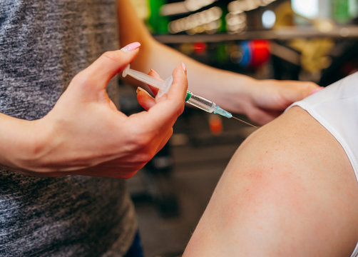 Doctor makes an injection to her boyfriend in gym