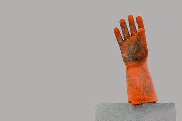 Schmutziger, orangefarbener Gummihandschuh auf einem Pfahl