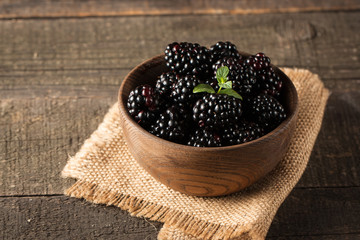 Fototapeta na wymiar Fresh organic ripe blackberries in a wooden bowl on wooden background. Healthy rustic food concept.
