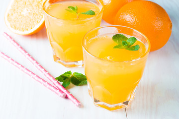 Close-up of a glass of orange juice with oranges fruits on wooden and stone background. Vitamins and minerals. Healthy drink and beverage concept.