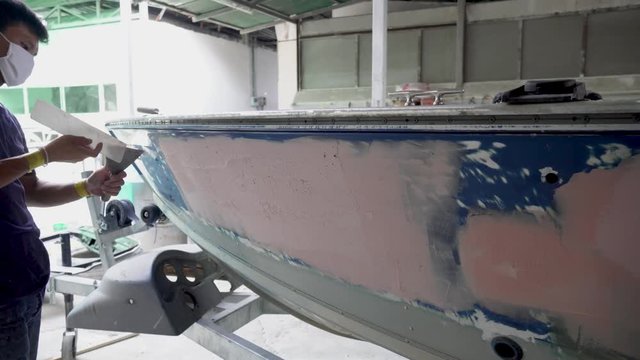 The mechanic repair the boat  , Using plastic putty ,Prepare surface for spray painting