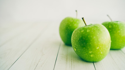 Juicy green apples on white background. Three apples with water drops on white wooden background	