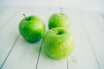 Juicy green apples on white background. Three apples with water drops on white wooden background