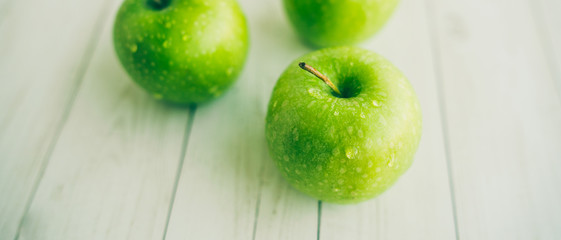 Juicy green apples on white background. Three apples with water drops on white wooden background
