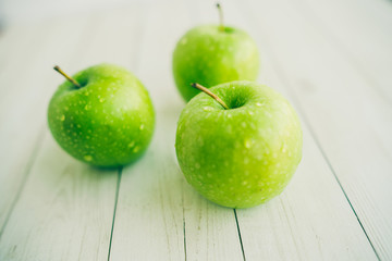 Juicy green apples on white background. Three apples with water drops on white wooden background