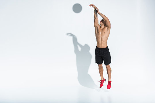 Athletic Mixed Race Man In Black Shorts And Red Sneakers Jumping On White Background