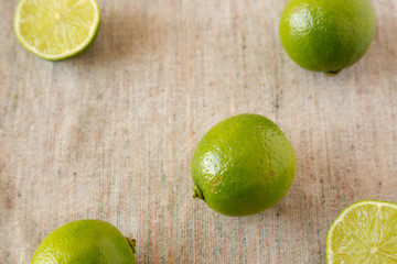 Whole and cut green citrus limes on cloth, low angle view.