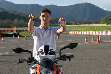 Teenage on the motorbike is showing driving license and motorcycle keys. Concept driving school for scooter