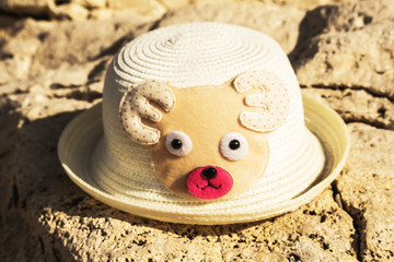 a kid  hat from the sun in the form of a bear bear lying on a rock on the beach, beach concept
