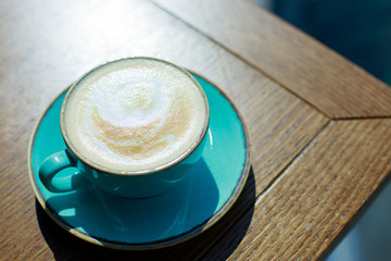Cappuccino with frothy foam. Coffee in blue cup on wooden table. Top view with copyspace for your...