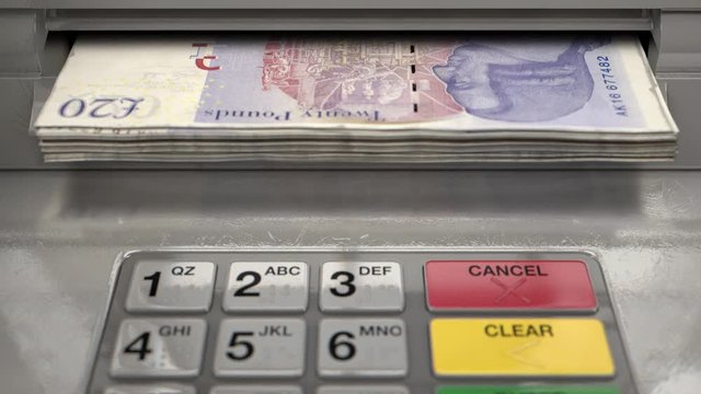 A closeup view of an atm facade with an illuminated sceen and keypad and a wad of united kingdom pound banknotes being ejected from the cash slot 