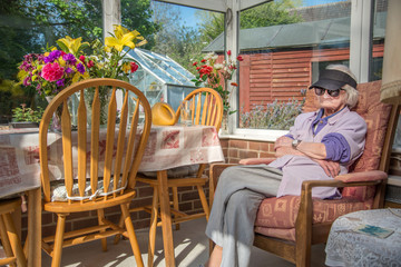Old woman with macular degeneration sitting in the sun at home.