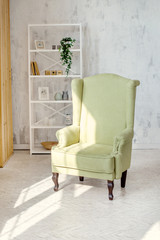 One classic olive armchair against a white wall and floor. Copy space. White sack. Scandinavian style