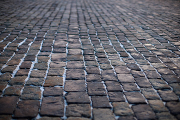 Fototapeta premium Stone pavement in perspective. Old street paved with stone blocks. Shallow depth of field. Vintage grunge texture.