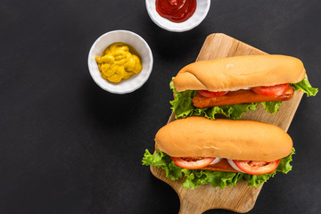 hot dogs on wooden cutting board and sauce in white cup